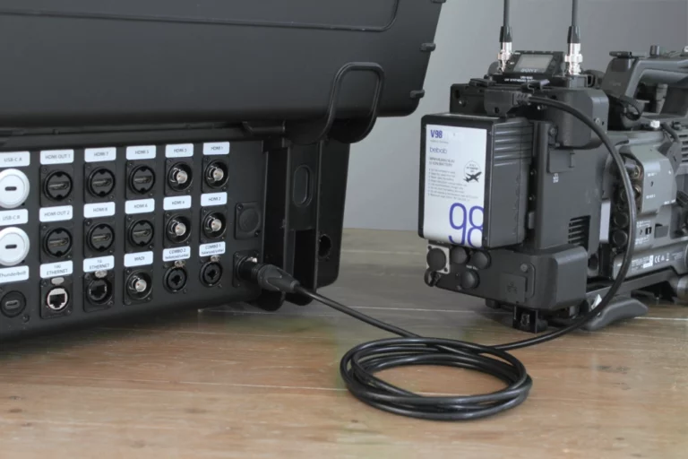Rückansicht eines ATEM Extreme G2 Transportkoffers mit 4-pin XLR-Anschluss, verbunden über ein D-Tap Kabel mit einem V-Mount Akku an einer professionellen Kamera für den mobilen Betrieb.
