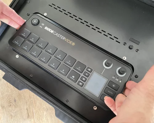 Rodecaster entnehmen Zwei Hände heben den Rodecaster Video aus dem Einbauschacht des BSS Case.